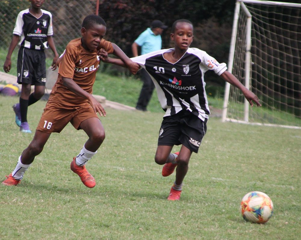 A Satino player shielding the ball from a Young Boys Academy opponent on the closing day of the Arumeru Youth League
